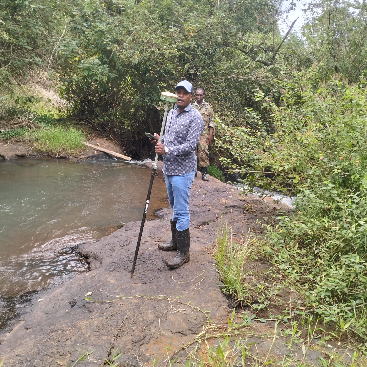 Erick Surveyors surveyor recording a GNSS boundary point beside a river in Kenya